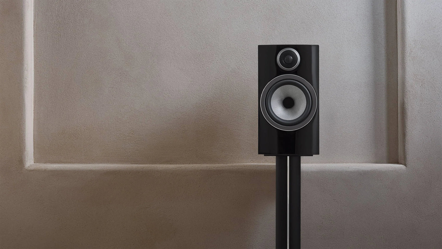 Gloss black 706 S3 speaker on a matching stand against a textured beige wall